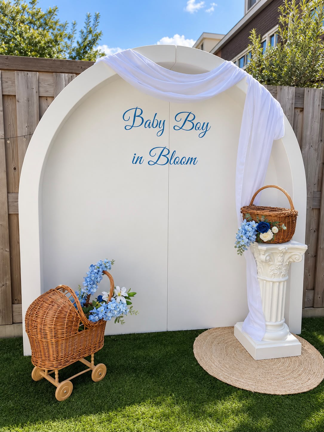 Witte boogbackdrop 'Baby Boy in Bloom' met rieten kinderwagen en blauwe bloemen