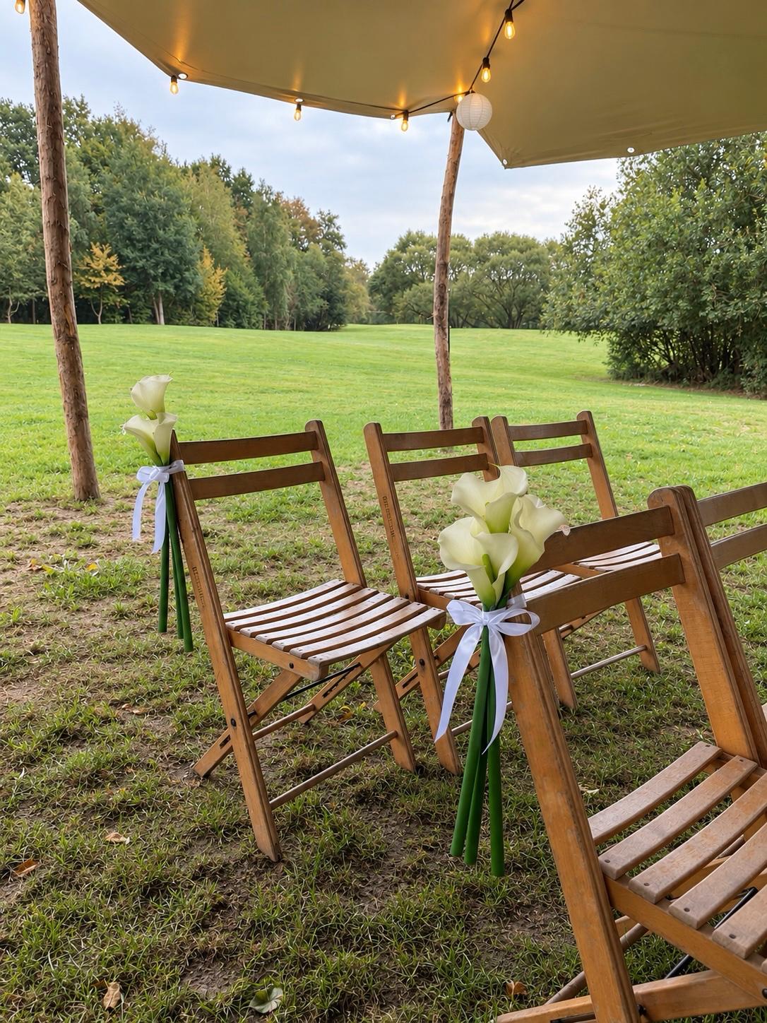 Buitenceremonie met houten klapstoelen en witte calla's met lint