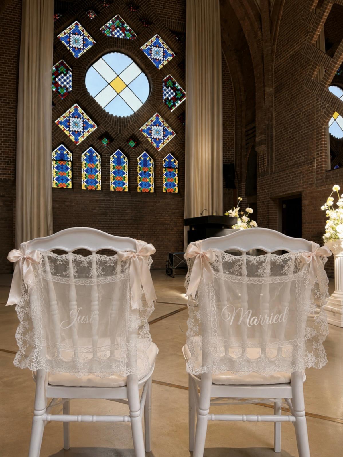 Twee witte stoelen met kanten 'Just Married' hoezen en satijnen strikken
