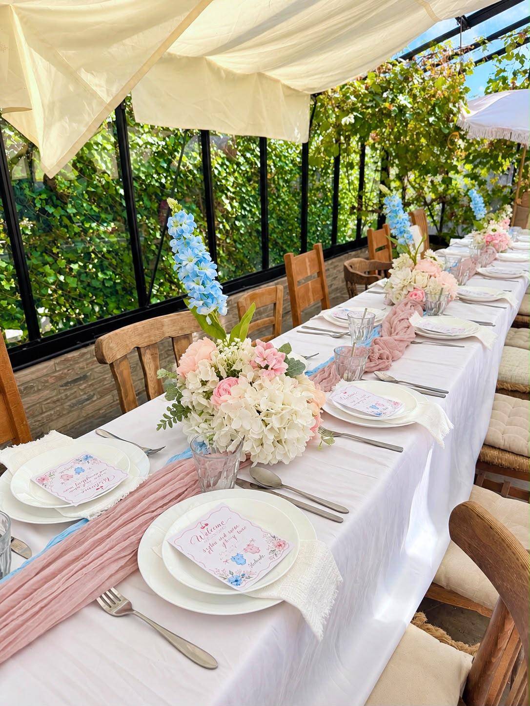 Babyshower tafel met roze en blauwe lopers, hortensia's en welkomstkaartjes